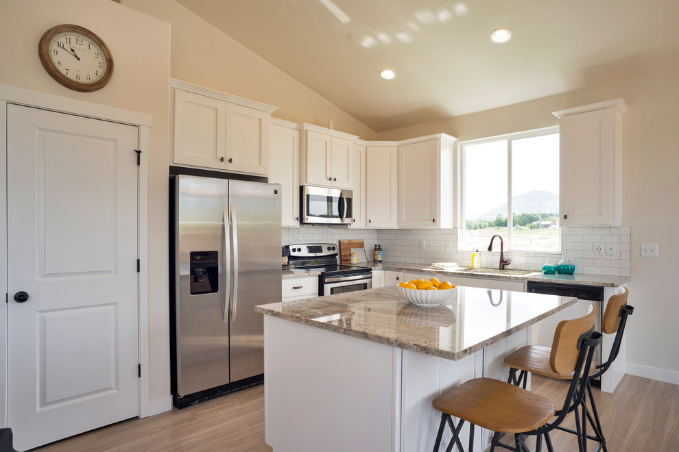 Inspiration for a laminate floor and beige floor kitchen remodel in Salt Lake City with shaker cabinets, white cabinets, granite countertops, white backsplash, ceramic backsplash, stainless steel appliances and an island