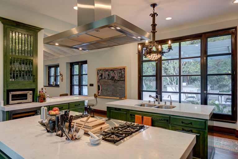 Large tuscan galley medium tone wood floor open concept kitchen photo in Los Angeles with a double-bowl sink, raised-panel cabinets, green cabinets, marble countertops, stainless steel appliances, two islands and white backsplash
