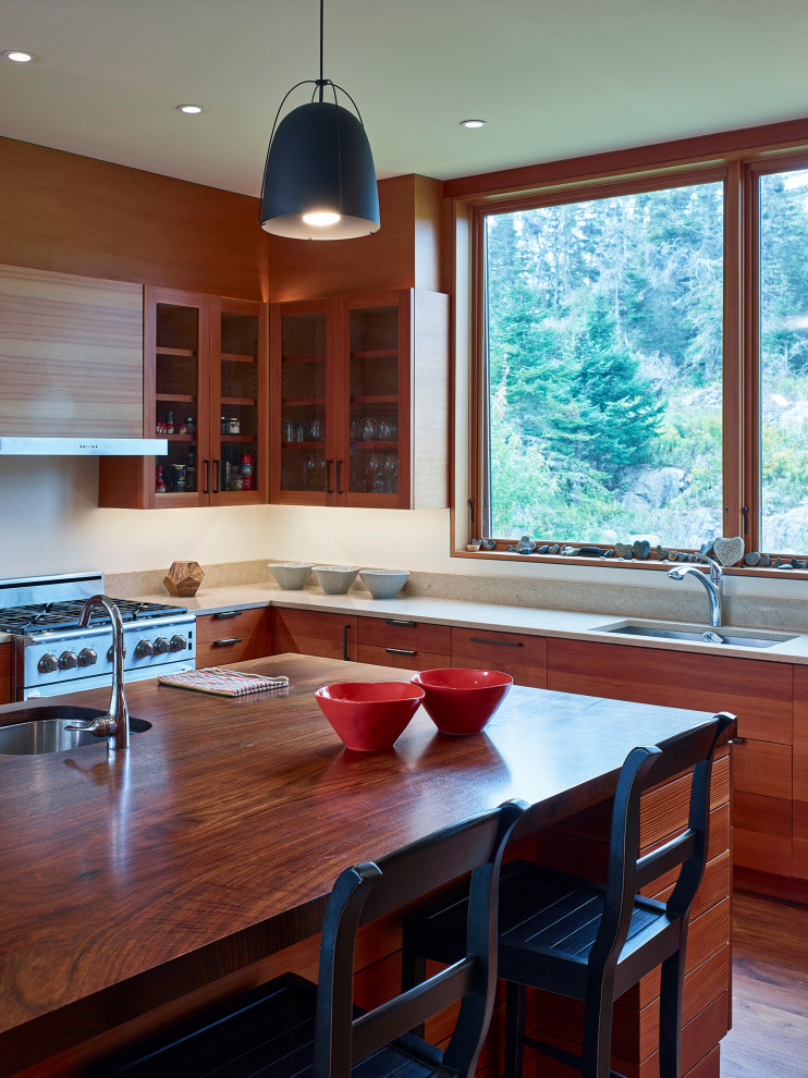 Bild på ett mellanstort funkis beige beige kök, med en enkel diskho, luckor med glaspanel, skåp i mellenmörkt trä, beige stänkskydd, rostfria vitvaror, mellanmörkt trägolv, en köksö och brunt golv