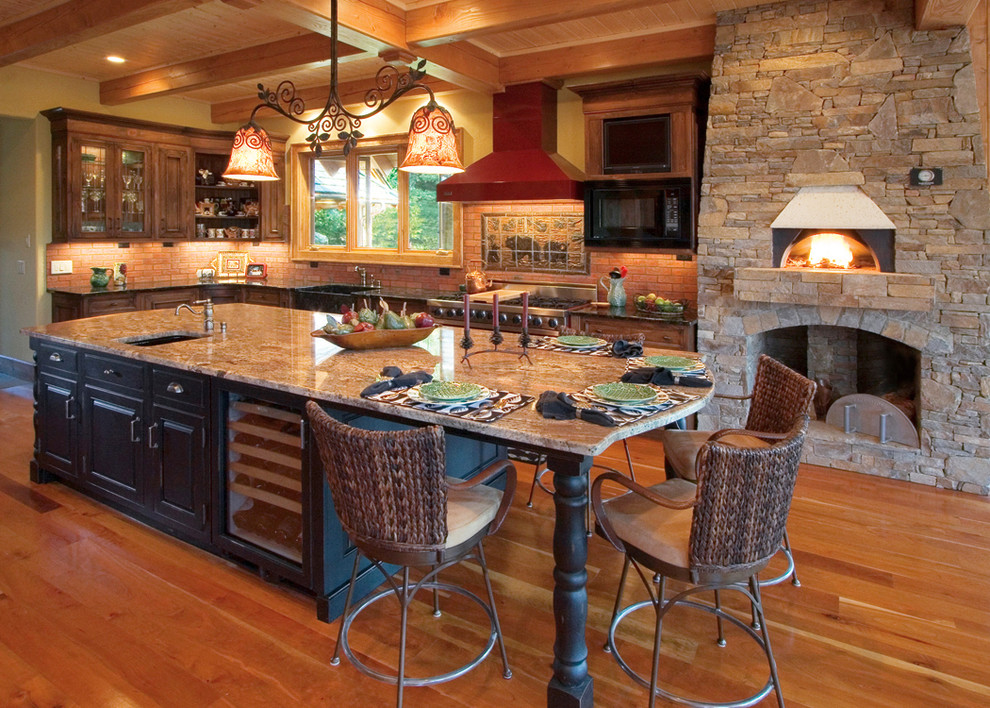Foto på ett stort amerikanskt kök, med en rustik diskho, luckor med infälld panel, skåp i mellenmörkt trä, granitbänkskiva, beige stänkskydd, stänkskydd i keramik, rostfria vitvaror, mellanmörkt trägolv och en köksö