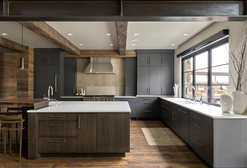Photo of a large rustic l-shaped kitchen/diner in Denver with a submerged sink, flat-panel cabinets, grey cabinets, grey splashback, stainless steel appliances, medium hardwood flooring, an island, brown floors and white worktops.