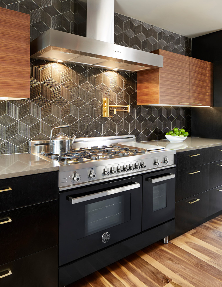 Mittelgroße Moderne Küche mit flächenbündigen Schrankfronten, Mineralwerkstoff-Arbeitsplatte, braunem Holzboden, schwarzen Schränken, bunter Rückwand und schwarzen Elektrogeräten in Dallas