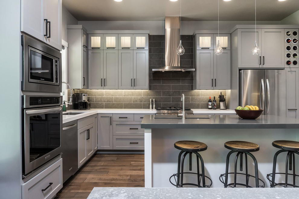 Eat-in kitchen - large modern l-shaped medium tone wood floor eat-in kitchen idea in Other with an undermount sink, shaker cabinets, gray cabinets, quartz countertops, gray backsplash, stone tile backsplash, stainless steel appliances and an island