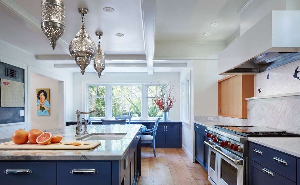 Exempel på ett stort eklektiskt kök, med en undermonterad diskho, släta luckor, blå skåp, marmorbänkskiva, vitt stänkskydd, stänkskydd i sten, rostfria vitvaror, ljust trägolv och en köksö