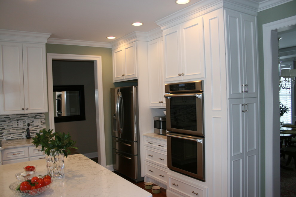 Modelo de cocina clásica renovada con puertas de armario blancas, encimera de cuarzo compacto y una isla