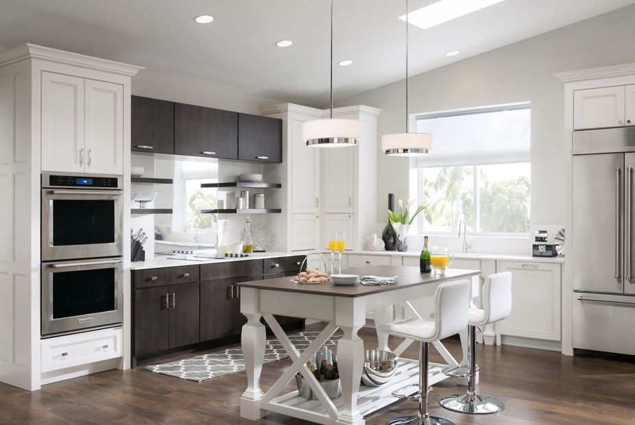 Design ideas for a medium sized traditional u-shaped enclosed kitchen in New Orleans with recessed-panel cabinets, white cabinets, composite countertops, metallic splashback, mirror splashback, stainless steel appliances, medium hardwood flooring and an island.
