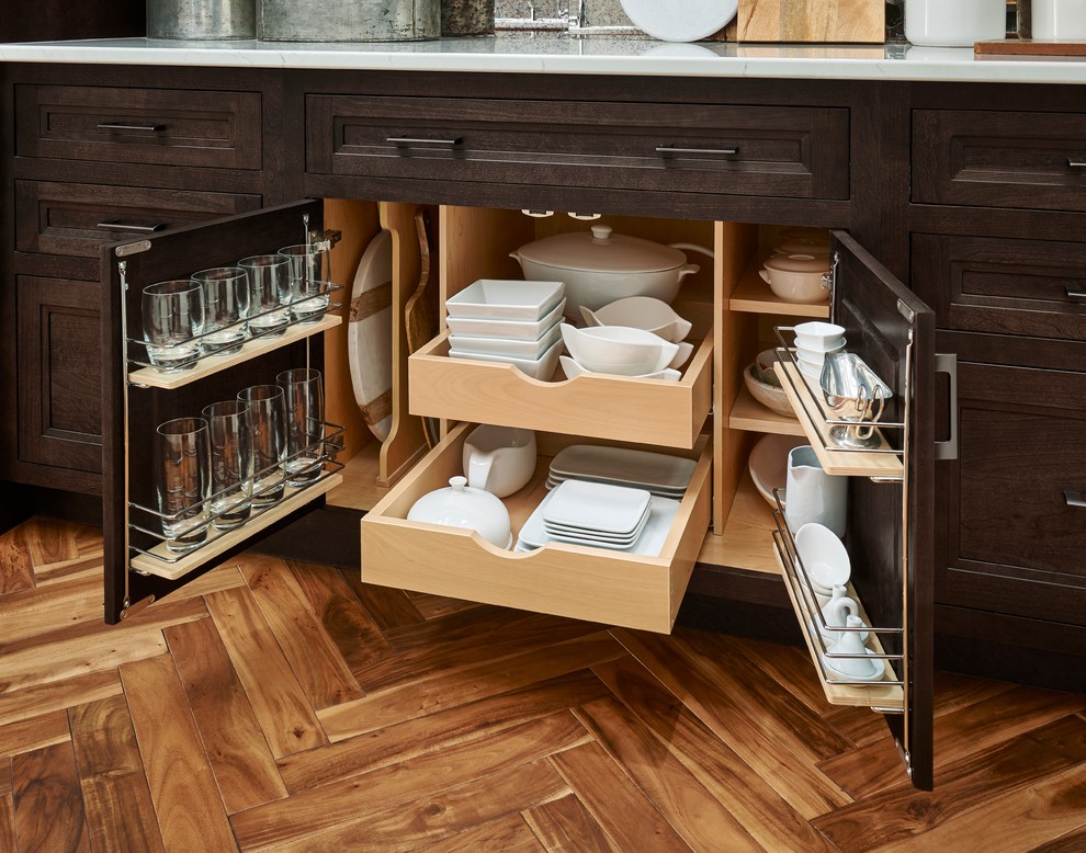 Cette image montre une cuisine traditionnelle en bois foncé avec un placard avec porte à panneau encastré, un plan de travail en quartz, un sol en bois brun et un sol marron.