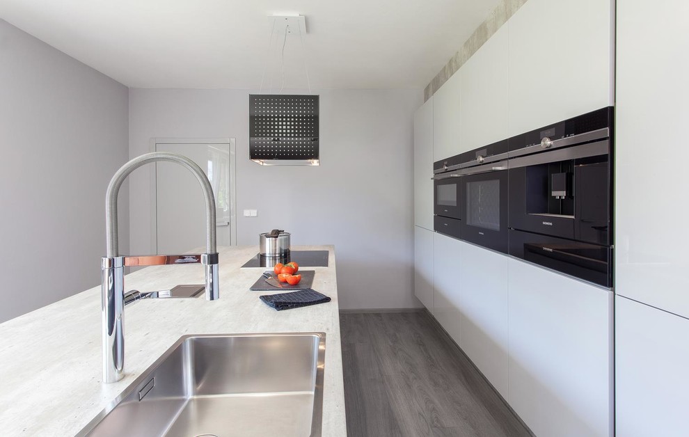 Einzeilige, Kleine Moderne Wohnküche mit flächenbündigen Schrankfronten, weißen Schränken, Küchengeräten aus Edelstahl und Kücheninsel in Charlotte