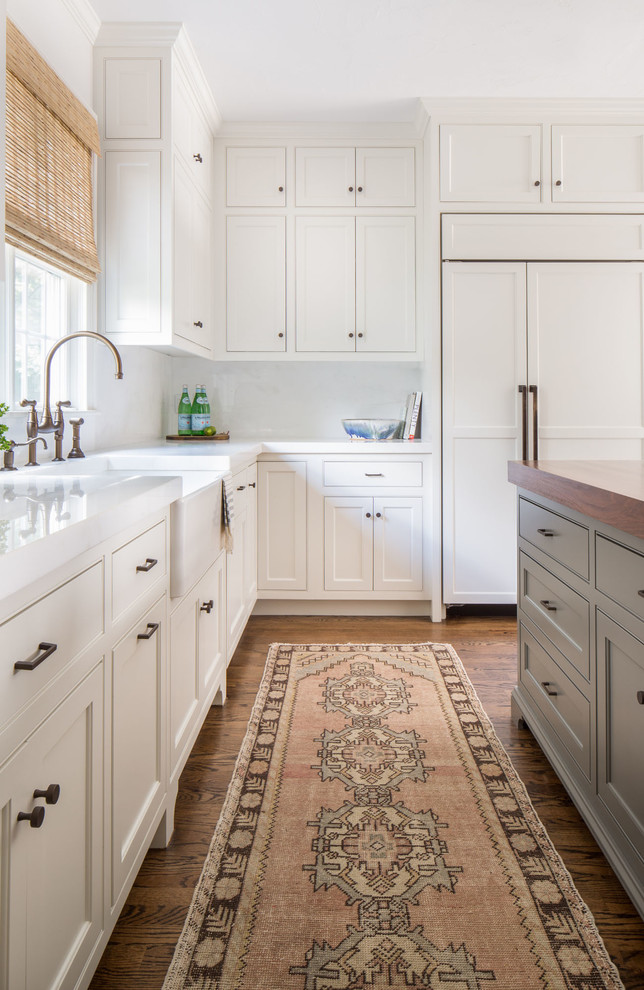 Landhaus Schmale Küche in L-Form mit Landhausspüle, Schrankfronten im Shaker-Stil, weißen Schränken, Elektrogeräten mit Frontblende, braunem Holzboden und Kücheninsel in Boston