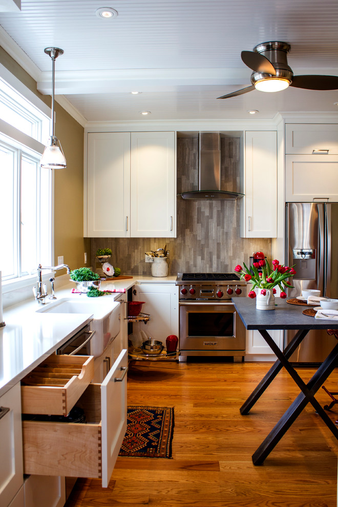 Klassische Küche mit Landhausspüle, Schrankfronten im Shaker-Stil, weißen Schränken, Küchenrückwand in Grau, Küchengeräten aus Edelstahl und braunem Holzboden in Boston