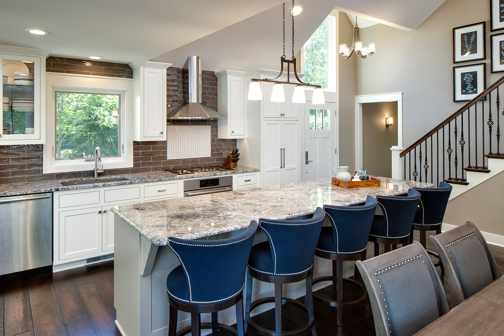 Large classic galley kitchen/diner in Minneapolis with a submerged sink, recessed-panel cabinets, white cabinets, granite worktops, grey splashback, stainless steel appliances, dark hardwood flooring and an island.