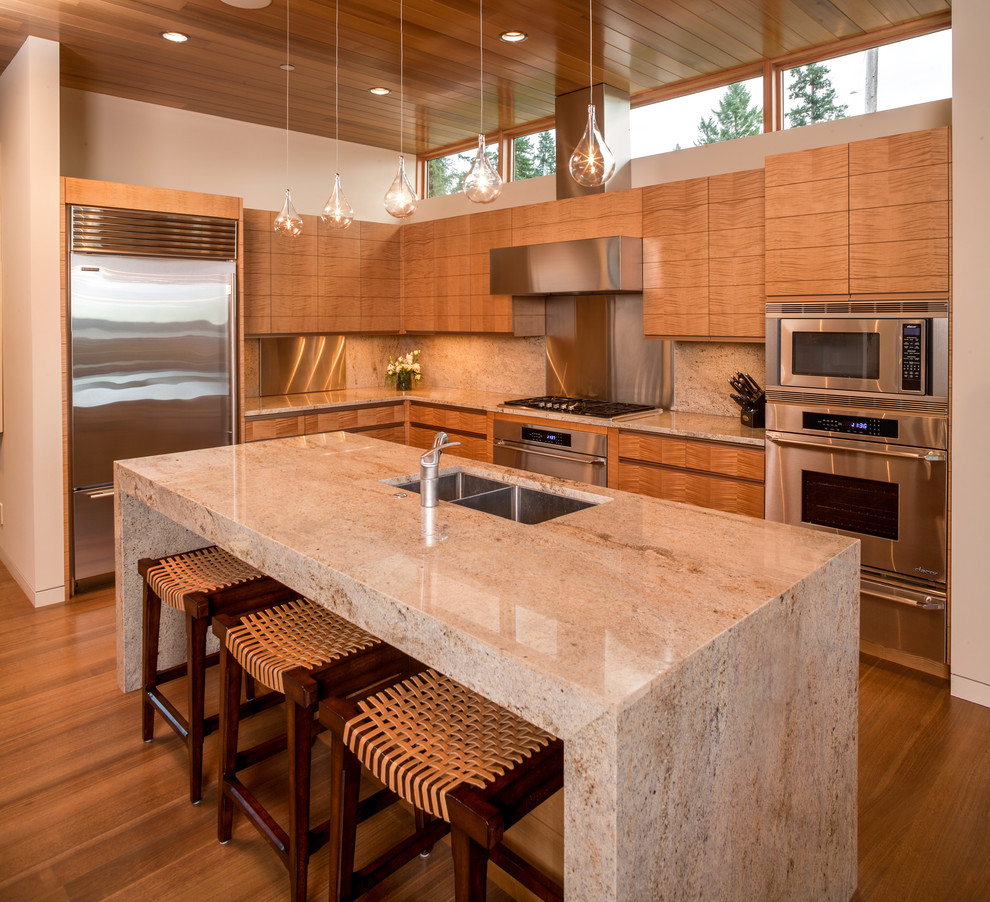 Example of a trendy l-shaped medium tone wood floor and brown floor kitchen design in Seattle with an undermount sink, flat-panel cabinets, medium tone wood cabinets, beige backsplash, stone slab backsplash, stainless steel appliances and an island