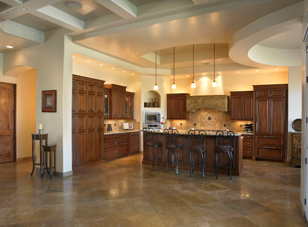 Exempel på ett mellanstort medelhavsstil l-kök, med luckor med upphöjd panel, skåp i mellenmörkt trä, brunt stänkskydd, stänkskydd i stenkakel, integrerade vitvaror, travertin golv, en köksö och brunt golv