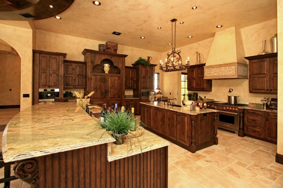 Large tuscan l-shaped travertine floor and beige floor kitchen photo in Orlando with an undermount sink, raised-panel cabinets, dark wood cabinets, quartzite countertops, beige backsplash, paneled appliances and two islands