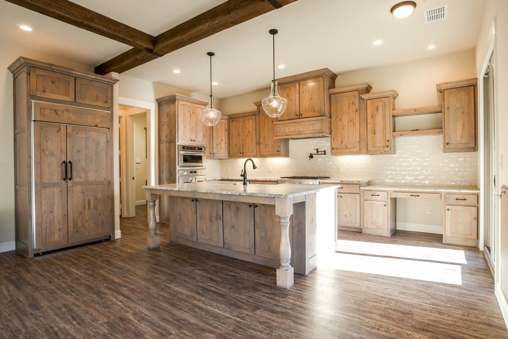 Large mountain style l-shaped medium tone wood floor open concept kitchen photo in Dallas with a farmhouse sink, shaker cabinets, light wood cabinets, concrete countertops, white backsplash, subway tile backsplash, stainless steel appliances and an island