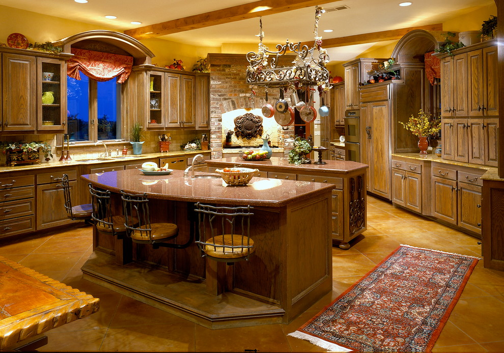 Example of a large classic u-shaped concrete floor eat-in kitchen design in Oklahoma City with an undermount sink, raised-panel cabinets, medium tone wood cabinets, granite countertops, beige backsplash, stone tile backsplash, paneled appliances and two islands