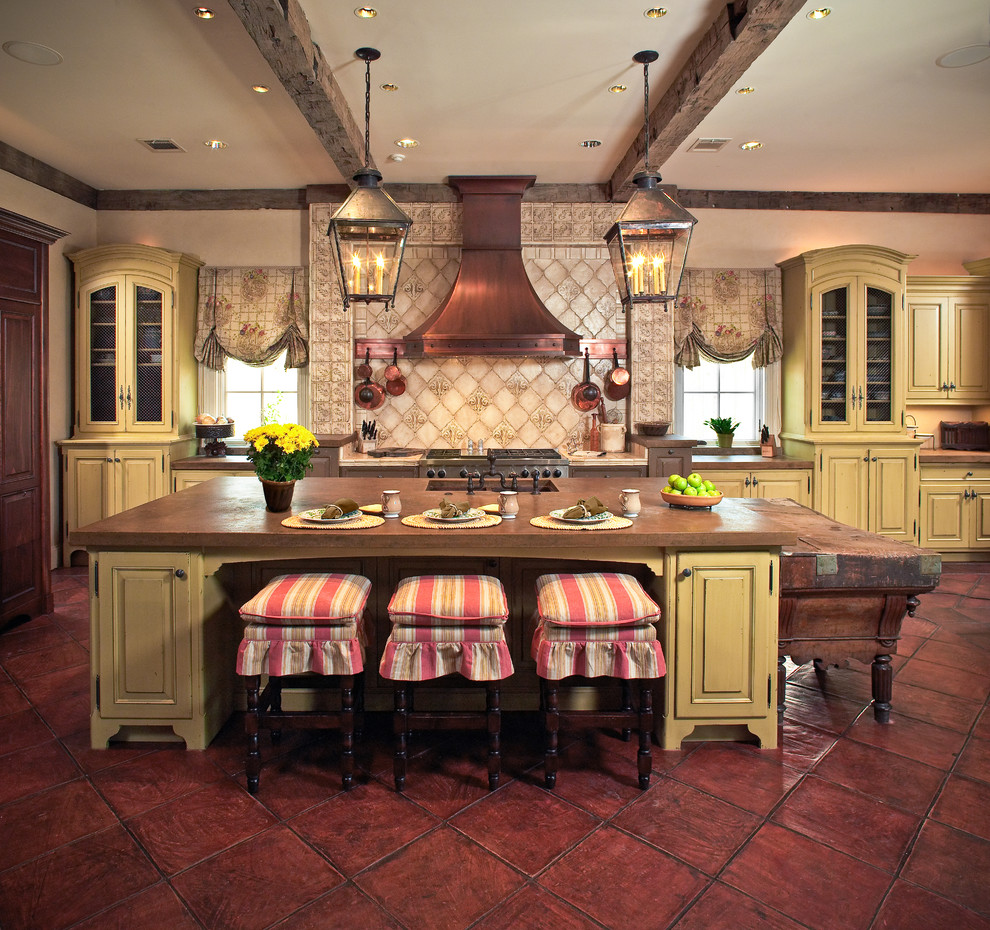 Bild på ett medelhavsstil kök, med luckor med upphöjd panel, gula skåp, beige stänkskydd och rostfria vitvaror