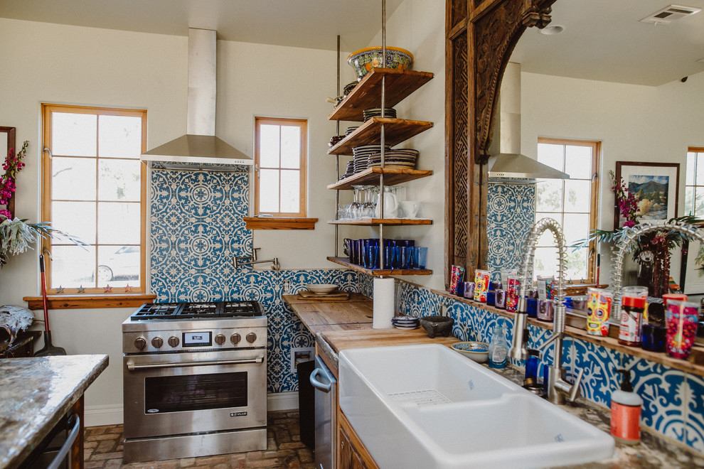 Photo of a mediterranean kitchen in Austin with a belfast sink, wood worktops, multi-coloured splashback, brick flooring and an island.