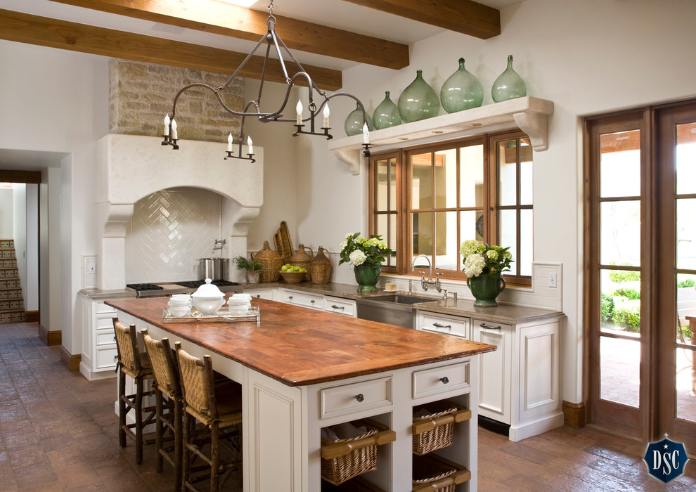 Inredning av ett medelhavsstil kök, med en rustik diskho, marmorbänkskiva, vitt stänkskydd och en köksö