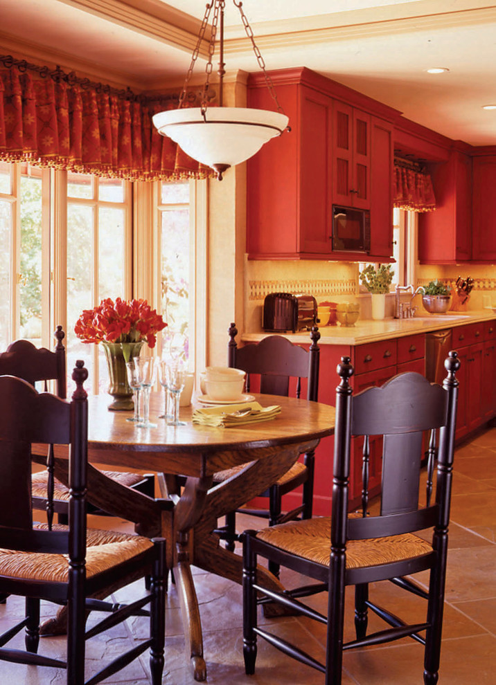 Exempel på ett mellanstort medelhavsstil kök, med luckor med infälld panel, röda skåp, granitbänkskiva, beige stänkskydd, stänkskydd i sten, rostfria vitvaror, klinkergolv i porslin, en köksö och beiget golv