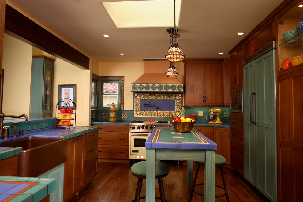 Idéer för ett medelhavsstil flerfärgad kök, med en rustik diskho, flerfärgad stänkskydd, kaklad bänkskiva, luckor med infälld panel, skåp i mörkt trä och integrerade vitvaror