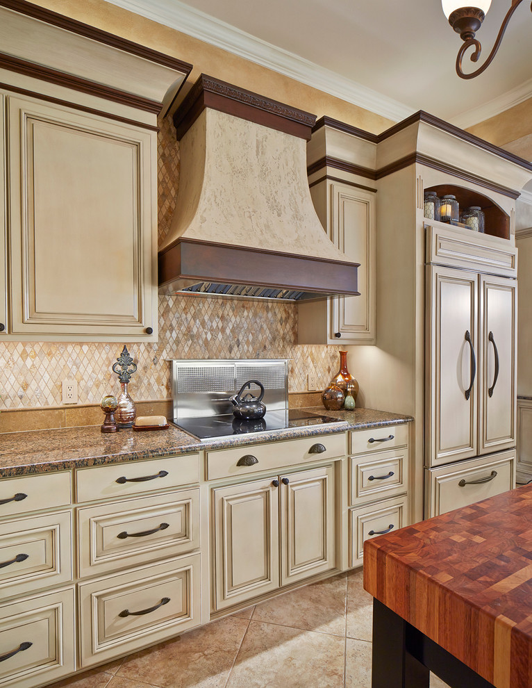 Example of a mid-sized tuscan l-shaped ceramic tile eat-in kitchen design in Dallas with a drop-in sink, beaded inset cabinets, white cabinets, granite countertops, beige backsplash, mosaic tile backsplash, black appliances and an island