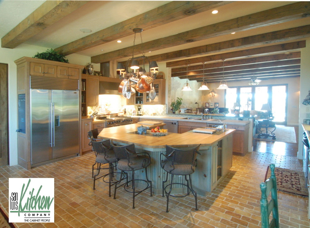 Идея дизайна: п-образная кухня-гостиная в средиземноморском стиле с накладной мойкой, светлыми деревянными фасадами, деревянной столешницей, зеленым фартуком, фартуком из керамической плитки и техникой из нержавеющей стали