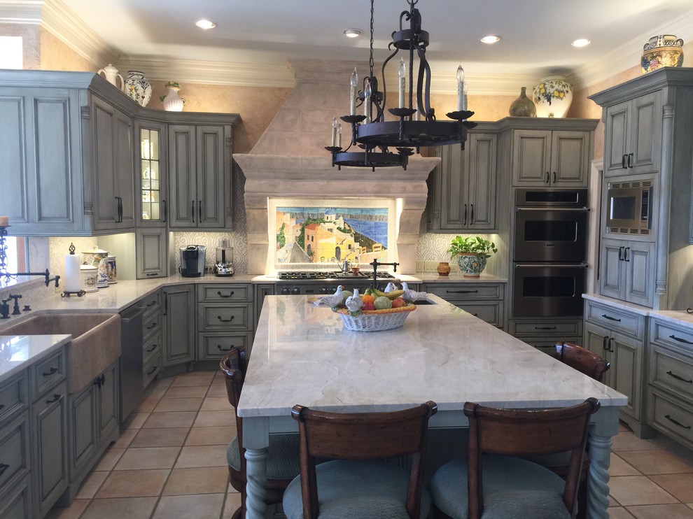 Huge tuscan u-shaped ceramic tile open concept kitchen photo in Other with a farmhouse sink, raised-panel cabinets, blue cabinets, quartzite countertops, beige backsplash, mosaic tile backsplash, stainless steel appliances and an island