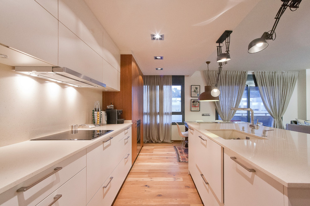 Mittelgroße Moderne Wohnküche mit flächenbündigen Schrankfronten, integriertem Waschbecken, weißen Schränken, Kücheninsel und braunem Holzboden in Barcelona