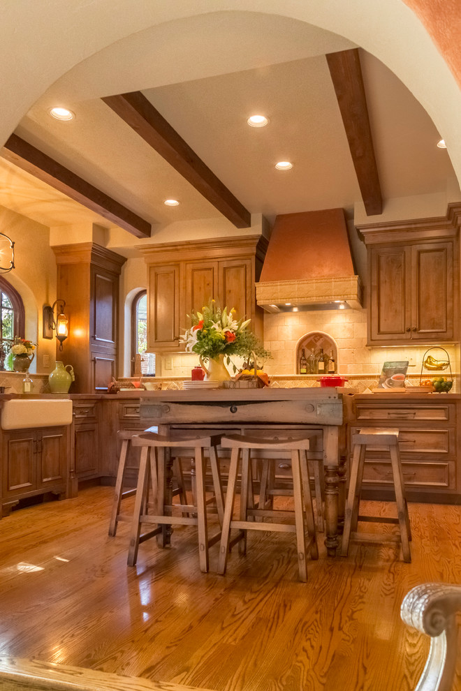 Example of a small tuscan l-shaped medium tone wood floor eat-in kitchen design in St Louis with a farmhouse sink, shaker cabinets, medium tone wood cabinets, concrete countertops, beige backsplash, stone tile backsplash, stainless steel appliances and an island