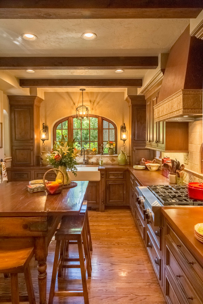 Small tuscan l-shaped medium tone wood floor eat-in kitchen photo in St Louis with a farmhouse sink, shaker cabinets, medium tone wood cabinets, concrete countertops, beige backsplash, stone tile backsplash, stainless steel appliances and an island