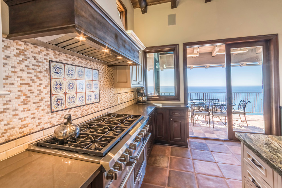 Inspiration for a large mediterranean u-shaped terra-cotta tile eat-in kitchen remodel in Orange County with a farmhouse sink, beaded inset cabinets, white cabinets, granite countertops, multicolored backsplash, stone tile backsplash, stainless steel appliances and an island