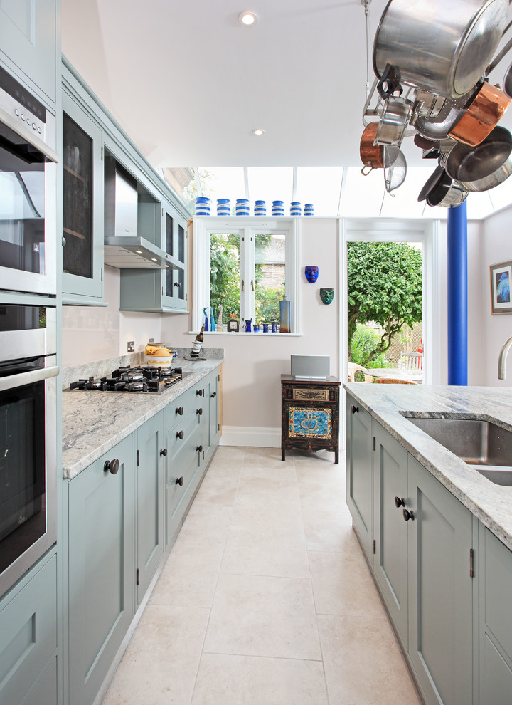 Idee per una cucina mediterranea di medie dimensioni con lavello a doppia vasca, ante in stile shaker, ante blu, top in granito, paraspruzzi beige, paraspruzzi con lastra di vetro e elettrodomestici in acciaio inossidabile