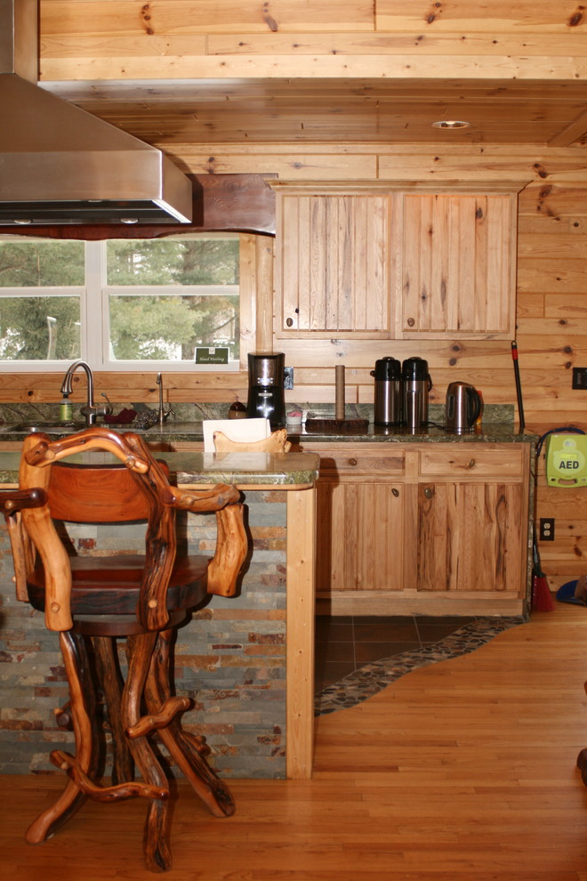 Cette image montre une grande cuisine américaine chalet en L et bois clair avec un évier 2 bacs, un placard à porte persienne, un plan de travail en granite, un électroménager en acier inoxydable, un sol en ardoise, îlot et un sol multicolore.