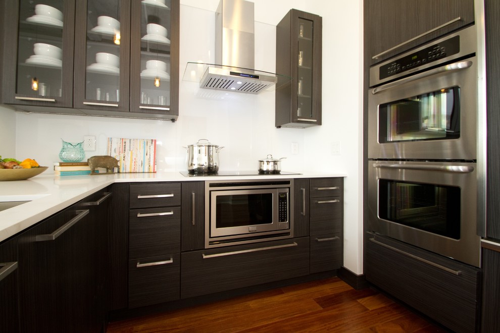 Imagen de cocina contemporánea con fregadero bajoencimera, armarios con paneles lisos, puertas de armario negras, encimera de cuarzo compacto, salpicadero blanco y electrodomésticos de acero inoxidable