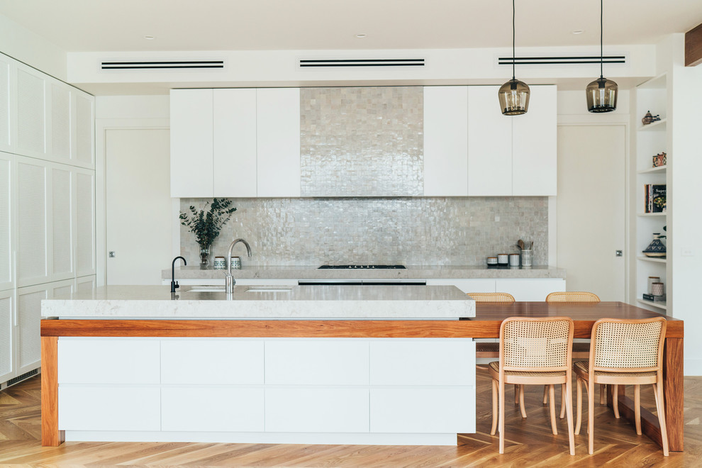 Inspiration for a large contemporary galley kitchen in Melbourne with a submerged sink, white cabinets, engineered stone countertops, grey splashback, mosaic tiled splashback, stainless steel appliances, light hardwood flooring and an island.