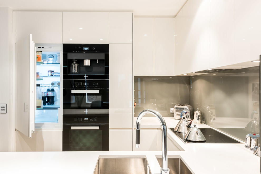 Design ideas for a small modern u-shaped kitchen/diner in Melbourne with a submerged sink, flat-panel cabinets, white cabinets, engineered stone countertops, glass sheet splashback, coloured appliances, no island and grey splashback.