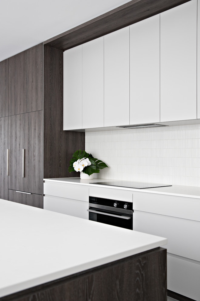 Foto på ett mellanstort funkis vit kök, med en undermonterad diskho, släta luckor, grå skåp, bänkskiva i kvarts, vitt stänkskydd, stänkskydd i mosaik, rostfria vitvaror, klinkergolv i porslin, en köksö och grått golv