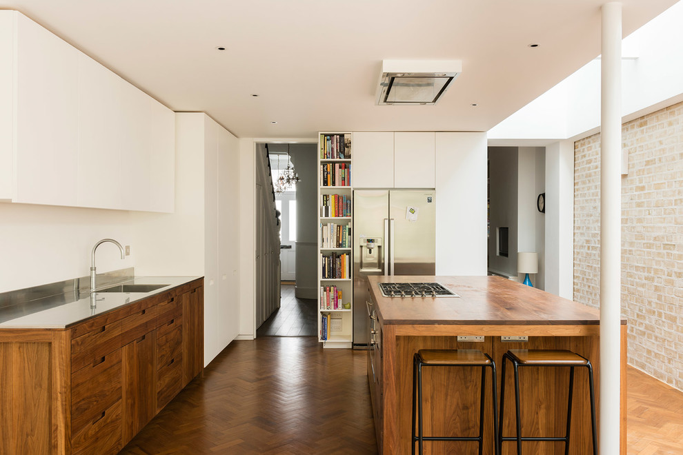 Inspiration for a medium sized contemporary u-shaped kitchen/diner in London with flat-panel cabinets, stainless steel appliances, medium hardwood flooring, an island, brown floors, an integrated sink, medium wood cabinets, wood worktops and brown worktops.