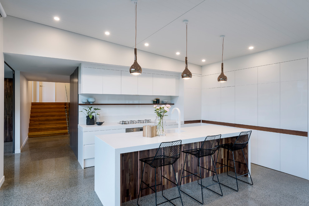 Idée de décoration pour une cuisine parallèle minimaliste avec un placard à porte plane, des portes de placard blanches, une crédence blanche, un électroménager en acier inoxydable, un sol en terrazzo, îlot et un sol gris.