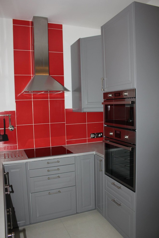 Bild på ett 60 tals kök, med en enkel diskho, luckor med upphöjd panel, grå skåp, laminatbänkskiva, rött stänkskydd, stänkskydd i keramik, svarta vitvaror och klinkergolv i porslin