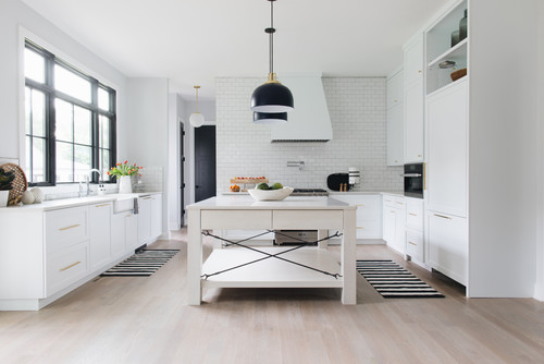 White Subway Backsplash in a Farmhouse Kitchen with White Shaker Cabinets and Black Pendants