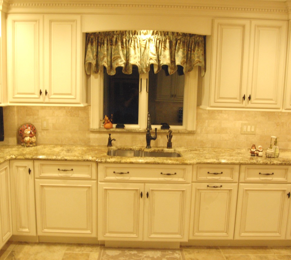 Example of a mid-sized classic l-shaped ceramic tile eat-in kitchen design in New York with an undermount sink, raised-panel cabinets, white cabinets, granite countertops, beige backsplash, ceramic backsplash, stainless steel appliances and no island
