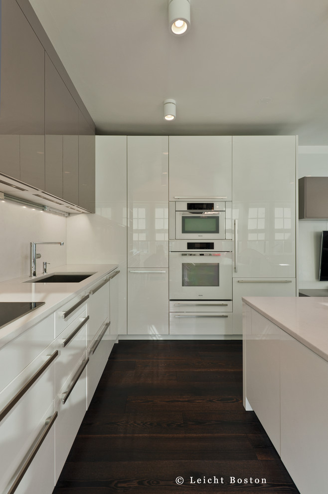 Kleine Moderne Küche mit Unterbauwaschbecken, flächenbündigen Schrankfronten, weißen Schränken, Quarzwerkstein-Arbeitsplatte, weißen Elektrogeräten und Kücheninsel in Boston
