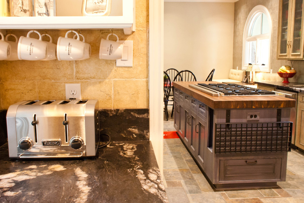 Immagine di una cucina design di medie dimensioni con ante di vetro, ante in legno chiaro, top in marmo, paraspruzzi con piastrelle in pietra e elettrodomestici in acciaio inossidabile