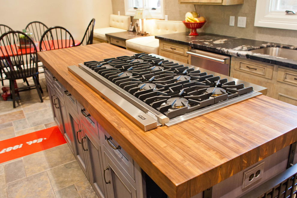 Foto di una cucina design di medie dimensioni con ante di vetro, ante in legno chiaro, top in legno e elettrodomestici in acciaio inossidabile