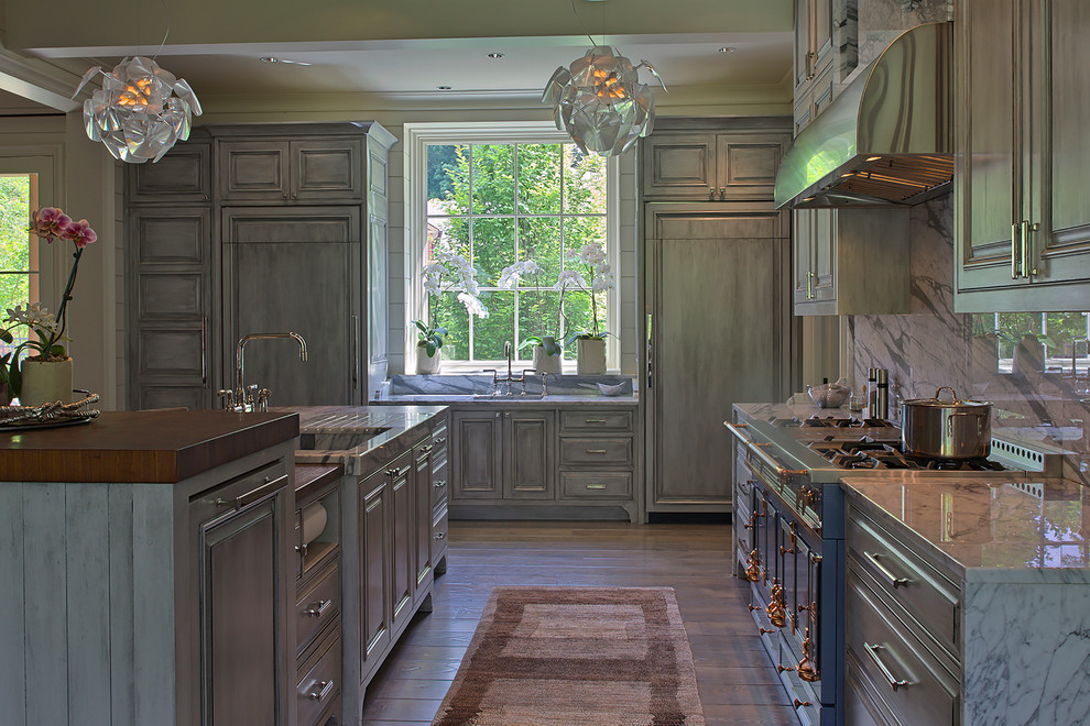 Idée de décoration pour une grande cuisine américaine tradition en L avec un évier encastré, des portes de placard grises, une crédence grise, un sol en bois brun et îlot.