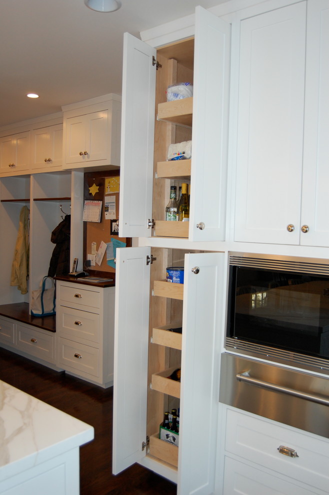 Foto de cocina clásica con armarios estilo shaker, puertas de armario blancas, encimera de mármol, electrodomésticos de acero inoxidable y suelo de madera oscura