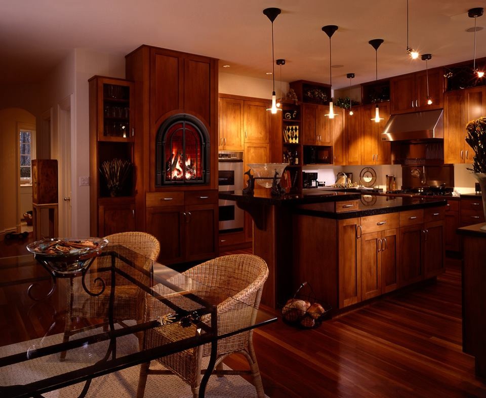 Klassisk inredning av ett stort kök, med en undermonterad diskho, luckor med infälld panel, skåp i mellenmörkt trä, bänkskiva i koppar, rostfria vitvaror, mörkt trägolv, en köksö och brunt golv