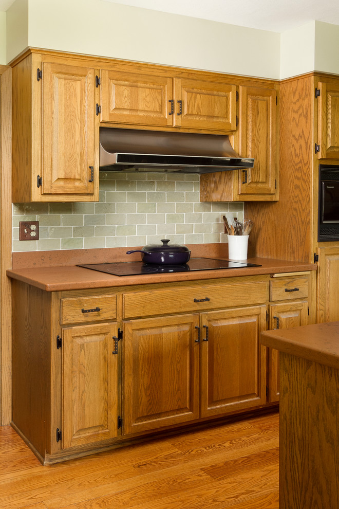 Idéer för ett mellanstort modernt kök, med luckor med upphöjd panel, skåp i mellenmörkt trä, grönt stänkskydd, stänkskydd i keramik, svarta vitvaror, mellanmörkt trägolv och en köksö